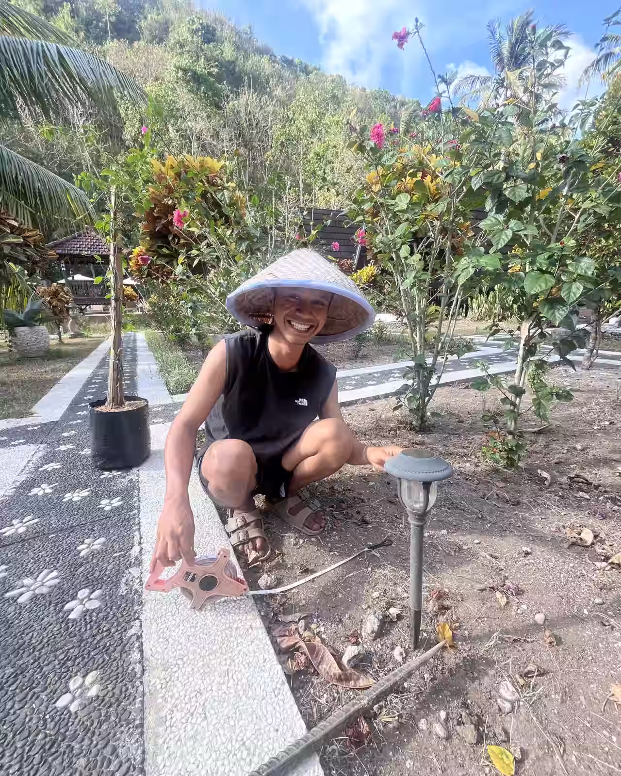 Nugraha, our housekeeper, smiling beside bougainvillea plants in the Mahaloka Valley garden in Nusa Penida.